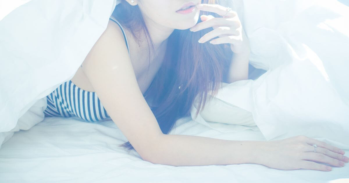 布団の中で顔を出す女性