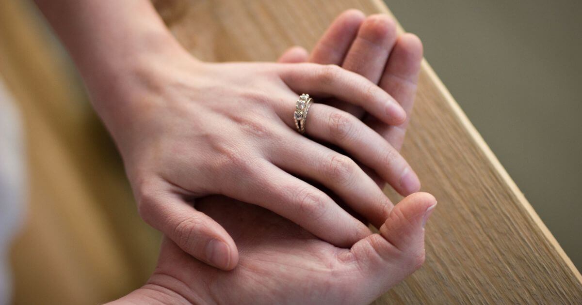 男性の手に重ねられた指輪をした人妻の手