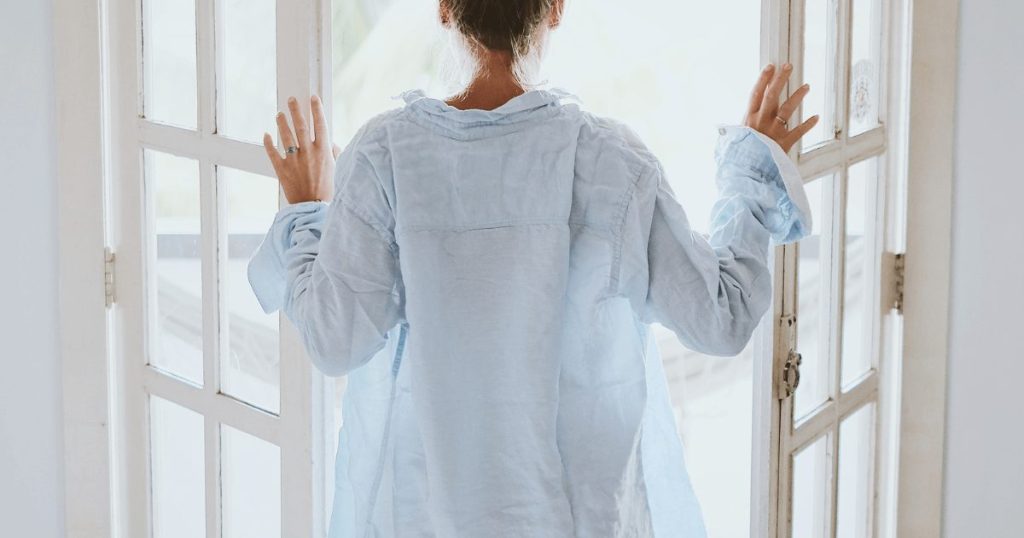 朝に寝巻姿でドアを開ける女性