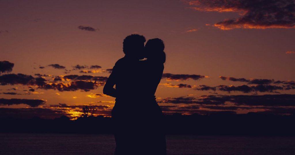 夕日をバックにキスをするカップル