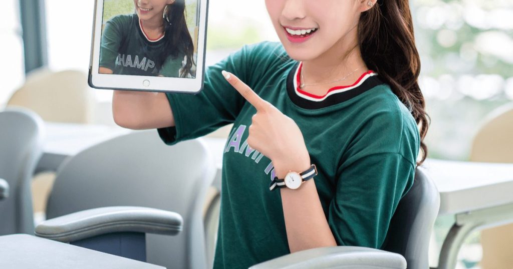 自分の写真が写ったタブレットを持つ女性